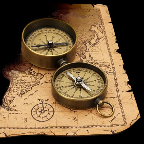 Vintage brass compass placed on an old antique paper map
